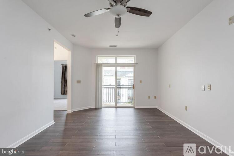 A spacious room with a ceiling fan and wooden flooring.