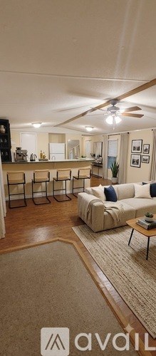 A living room with a beige couch and a rug.