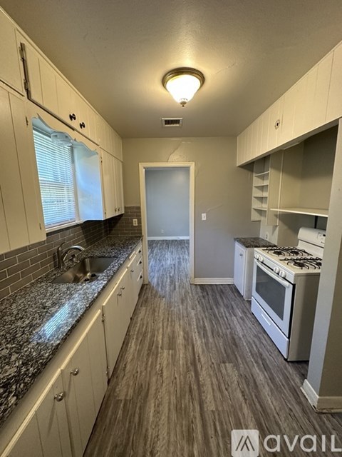 A kitchen with white cabinets and a granite countertop.