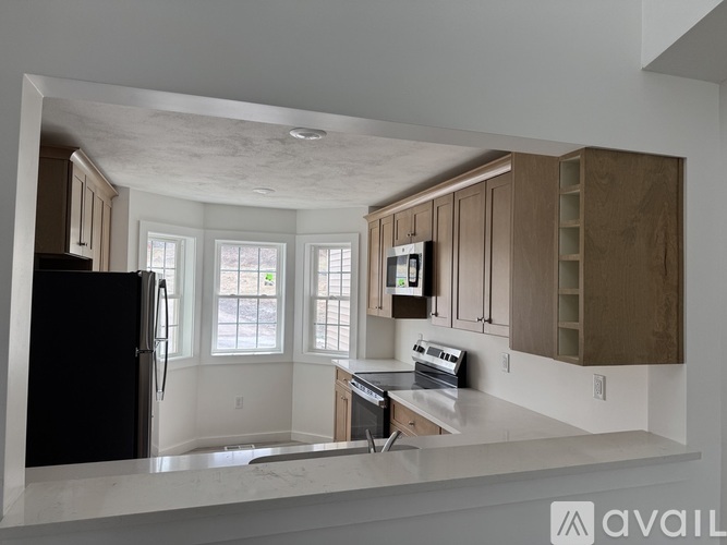 A kitchen with a black refrigerator and wooden cabinets.