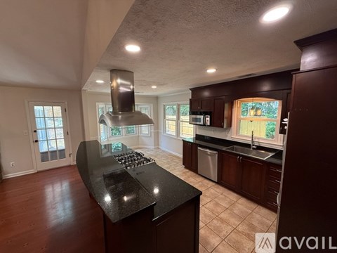 A kitchen with dark wood cabinets and a black countertop.