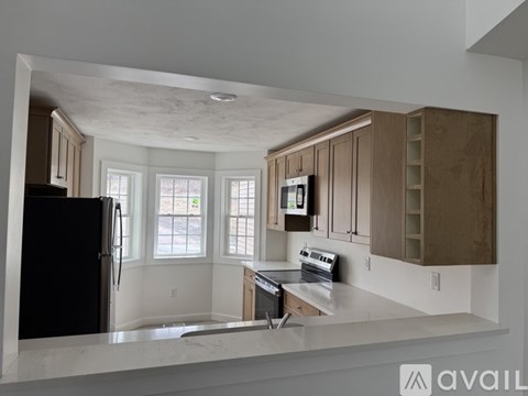A kitchen with a black refrigerator and wooden cabinets.