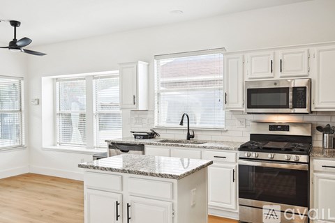 A kitchen with white cabinets and a granite countertop.