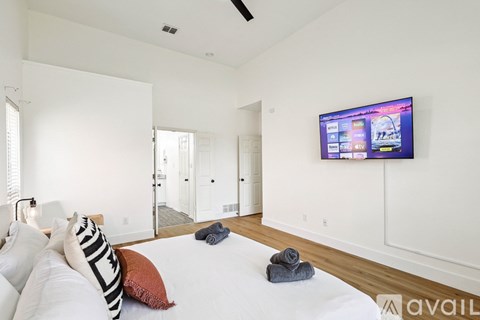 A bedroom with a large bed and a flat screen TV mounted on the wall.
