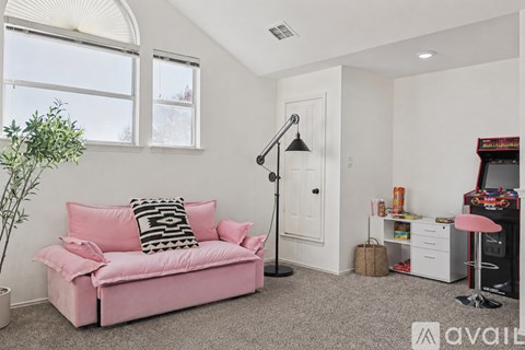 A living room with a pink couch and a plant.