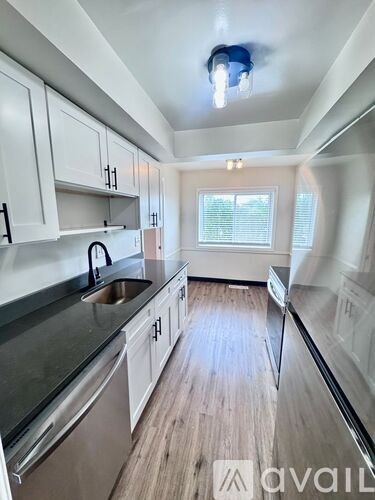 A kitchen with white cabinets and a stainless steel refrigerator.