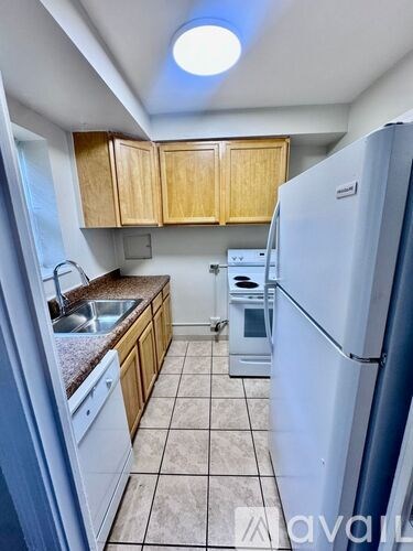 A kitchen with a white refrigerator, brown cabinets, and a white oven.