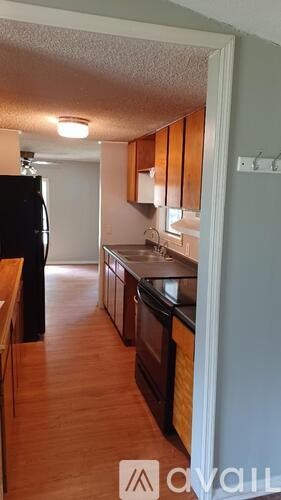 A kitchen with wooden cabinets and a black refrigerator.