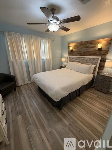 A bedroom with a bed, dresser, and ceiling fan.