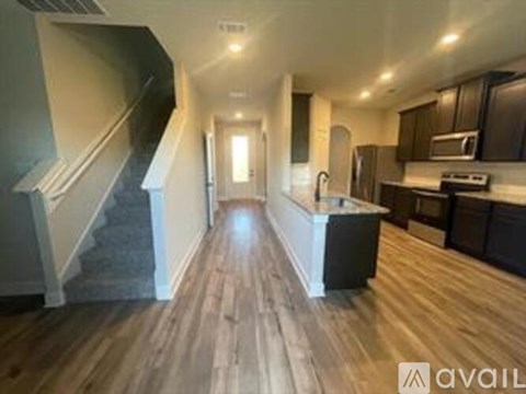 A modern kitchen with dark wood cabinets and a light wood floor.