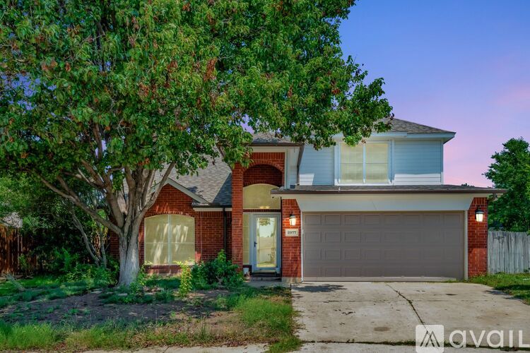 A house with a red brick facade and a large tree in front.
