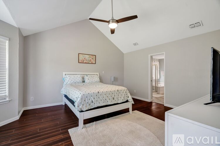 A bedroom with a bed, a ceiling fan, and a television.