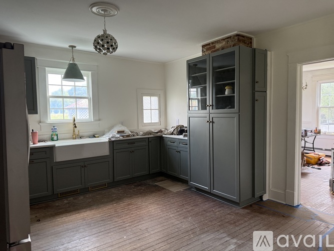 A kitchen with grey cabinets and a wooden floor.
