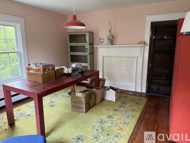A room with a table, chairs and boxes on the floor.