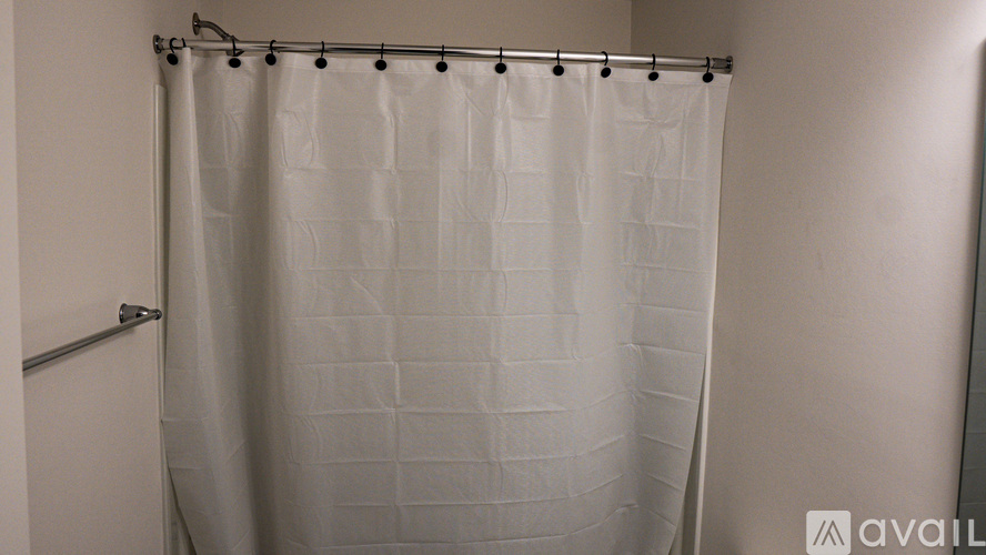 A white shower curtain with a grid pattern hangs in a bathroom.