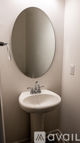 A bathroom sink with a round mirror above it.
