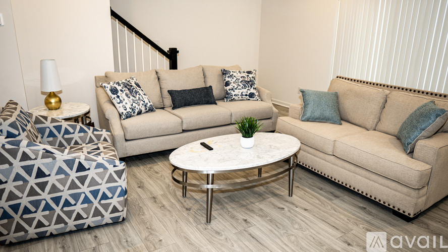 A living room with a beige couch, a white coffee table, and a patterned ottoman.