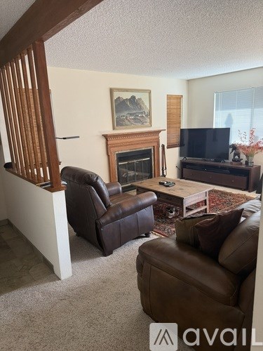 A living room with a brown leather couch and a fireplace.