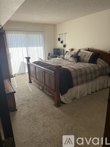 A bedroom with a large bed and a window with blinds.