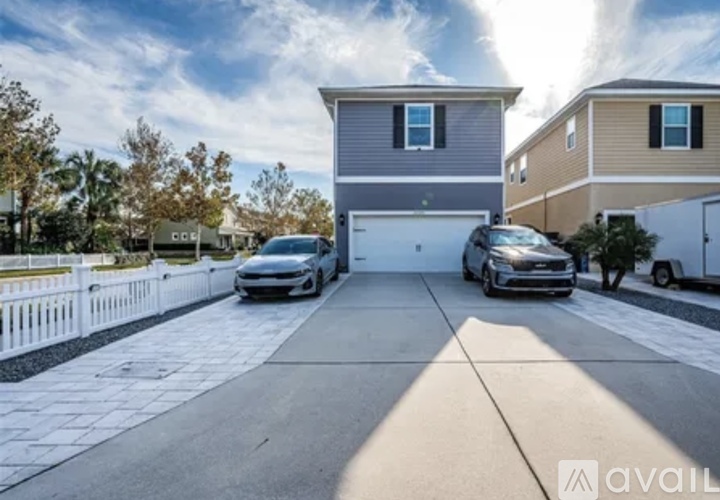 A house with a grey and white exterior is shown with two cars parked in the driveway.