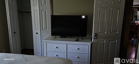 A bedroom with a bed, dresser and a television.