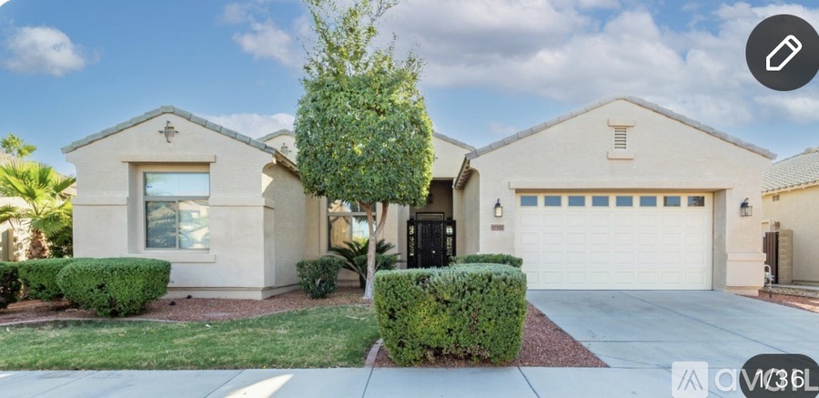 A house with a white garage door and a tree in front.