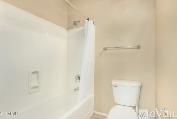 A white toilet in a bathroom with a white tub and shower curtain.