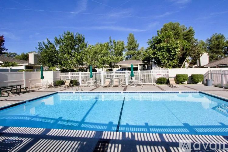 A large outdoor swimming pool surrounded by a fence and trees.