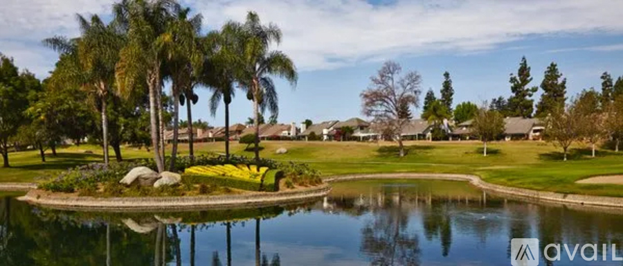 A golf course with a pond and palm trees.