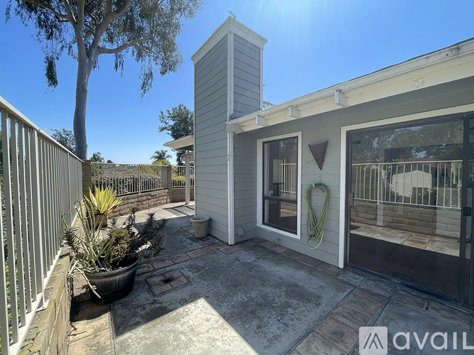 A patio area with a white fence and a grey house.