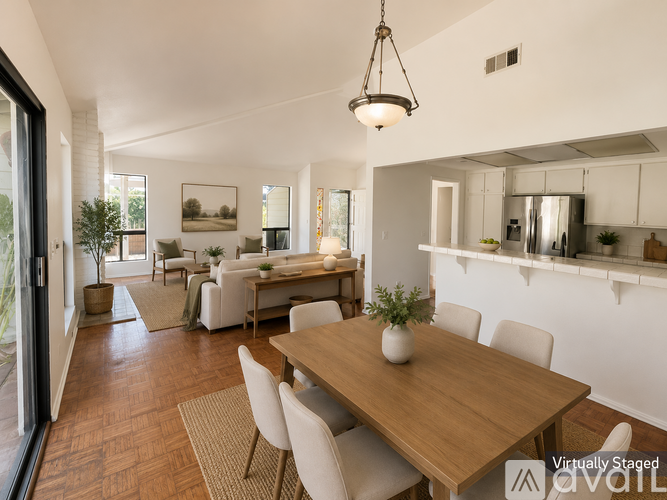 A modern dining room with a wooden table and white chairs.