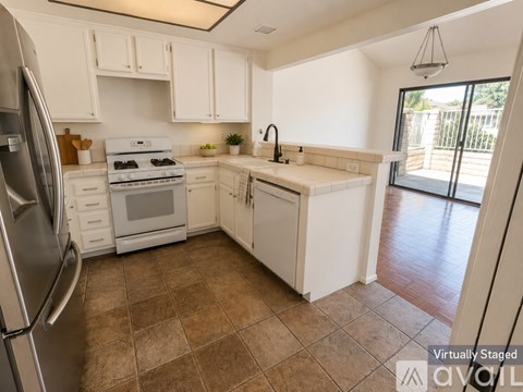 A kitchen with white cabinets and a tiled floor.