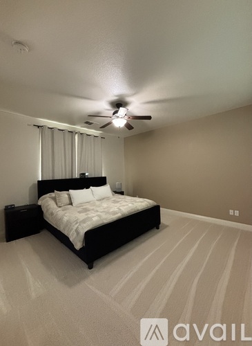 A bedroom with a large bed and a ceiling fan.