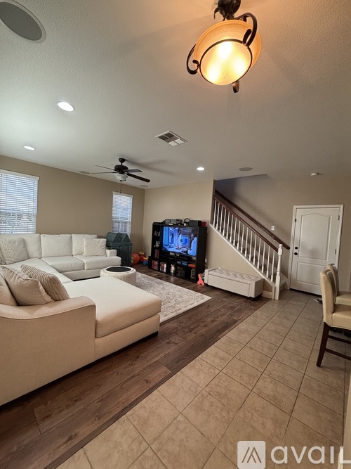 A living room with a white couch and a television on the wall.