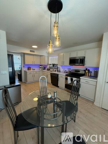 A modern kitchen with a glass dining table and chairs.