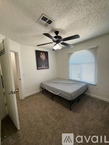 A bedroom with a bed, a ceiling fan, and a picture on the wall.