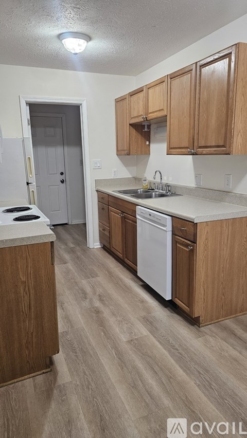 A kitchen with wooden cabinets and a white dishwasher.