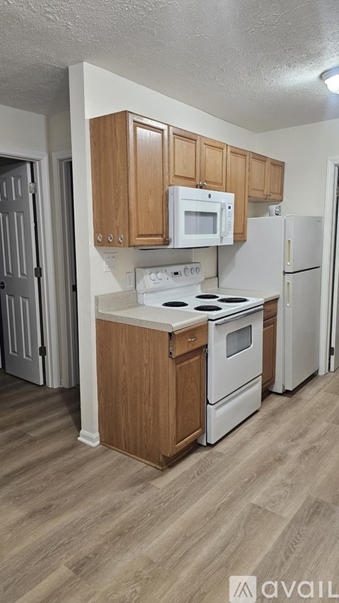 A kitchen with white appliances and wooden cabinets.