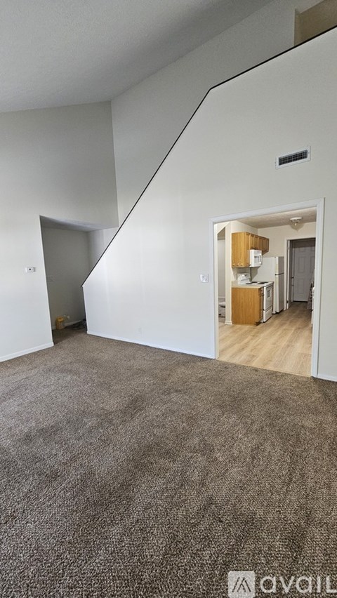 A room with a carpeted floor and a staircase leading to another room.