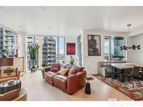 A living room with a brown leather couch and a dining table with chairs.