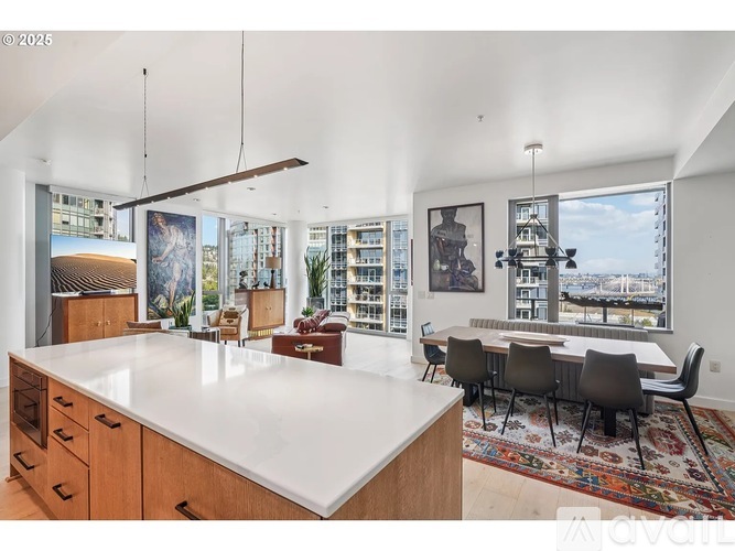 A modern kitchen with a large island and a dining table with chairs.