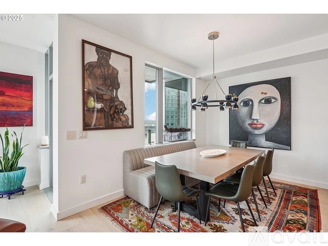 A dining room with a table and chairs and a painting on the wall.