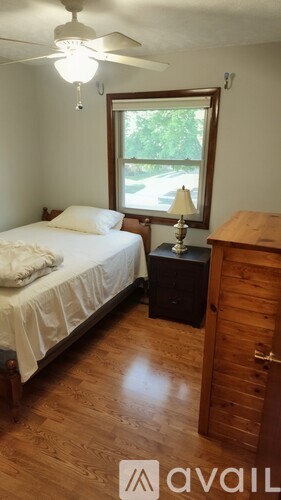A bedroom with a bed, nightstand, and a window.