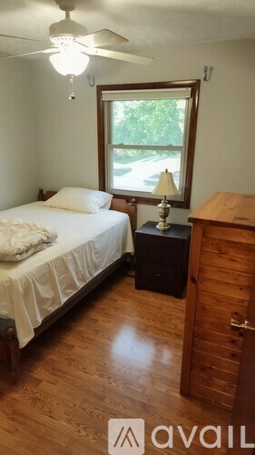 A bedroom with a bed, nightstand, and a window.