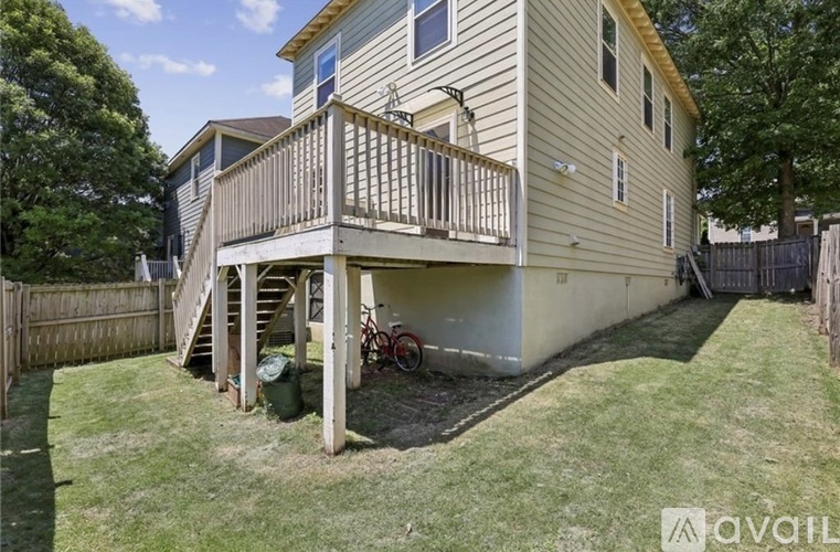 A two-story house with a deck and a bicycle parked on the grass.