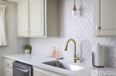 A kitchen with a white sink and a white wall.