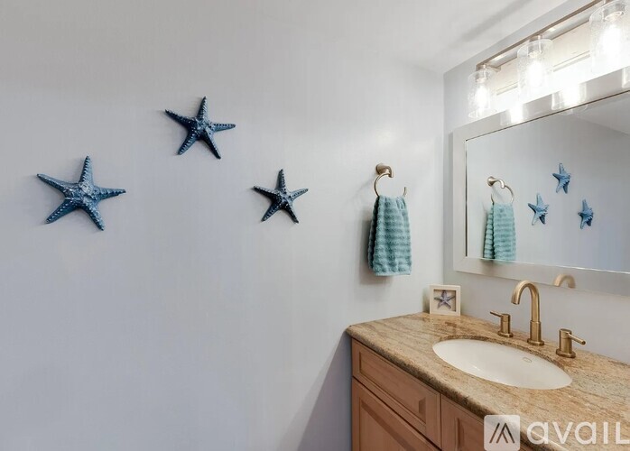 A bathroom with a sink, mirror, and starfish decorations.