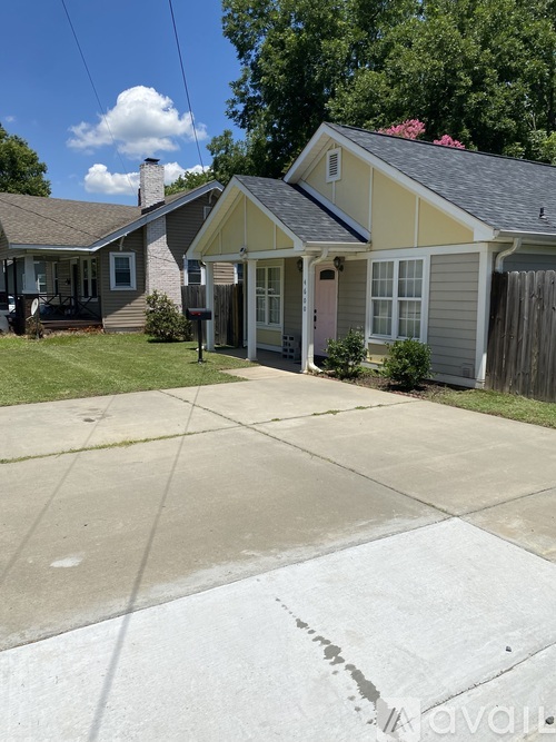 A house with a grey roof and a yellow house in the background.