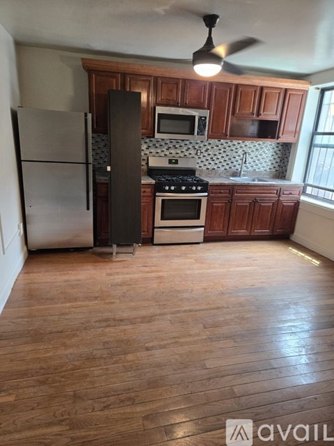 A kitchen with wooden cabinets and a stainless steel refrigerator.