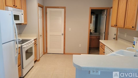 A kitchen with white appliances and wooden cabinets.